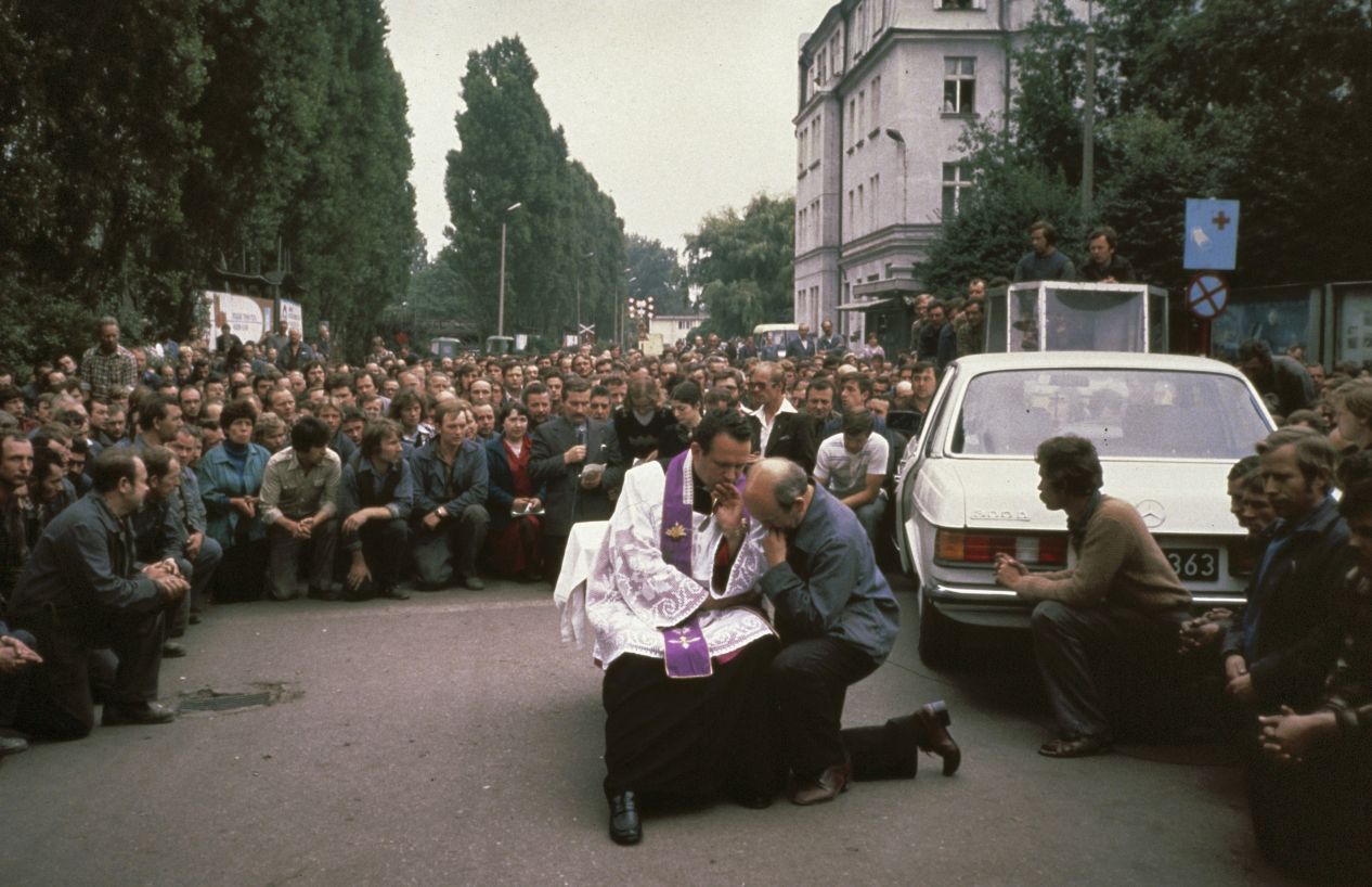 Priester Henryk Jankowski spendet am 20. August 1980 auf der Leninwerft in Gdańsk die Beichte; hinter ihm steht Streikführer Lech Wałęsa mit Mikrofon.